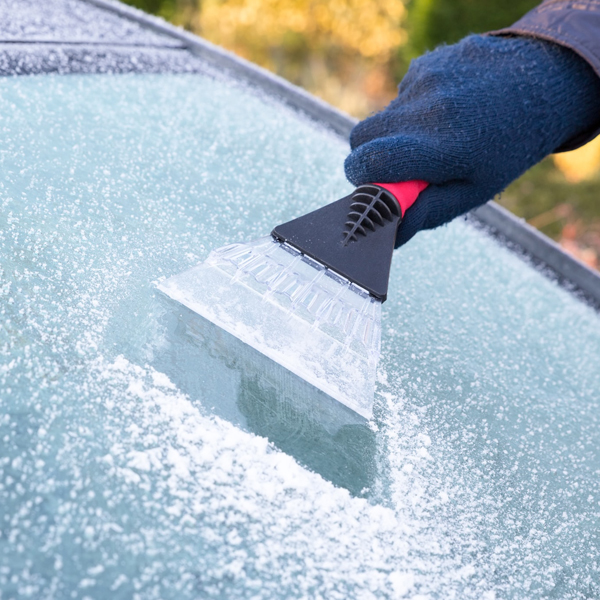 Someone scrapping frozen rain off of their vehicles windshield