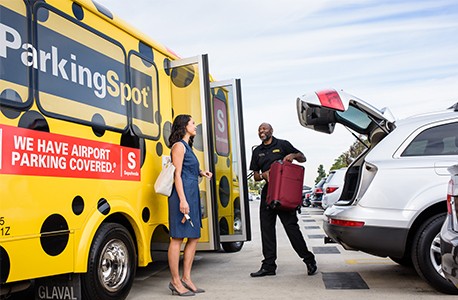 Parking Spot shuttle driver handing woman her suitcase outside shuttle