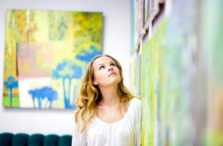 Woman looking at paintings in art gallery