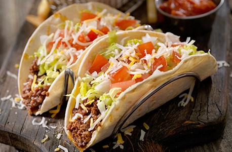 Two beef tacos with lettuce, cheese, and tomatos