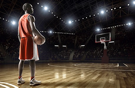 Basketball player on a court with the lights dimmed and spectators watching