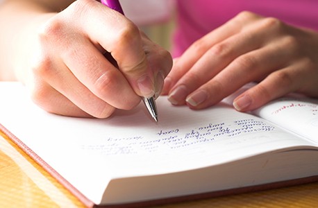 A person's hands as they write in a book