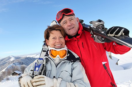 A male and female AAA member at the top of a ski mountain