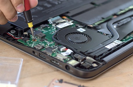 A hand holding a screwdriver as it fixes a piece of electronic equipment