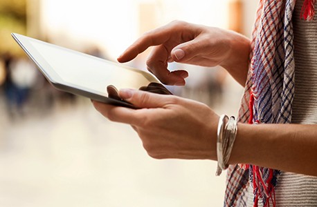 A close-up of the hands of a AAA member using a tablet