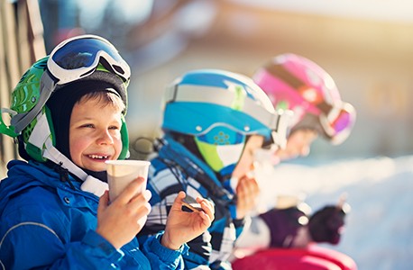 Three children in ski gear drinking hot cocoa
