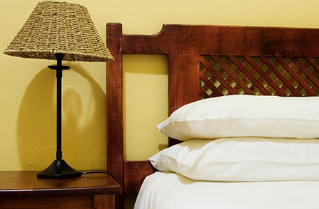 a photo of a bed with pillows, a lamp, and bedside table