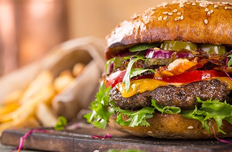 close up of a hamburger with french fries in the background