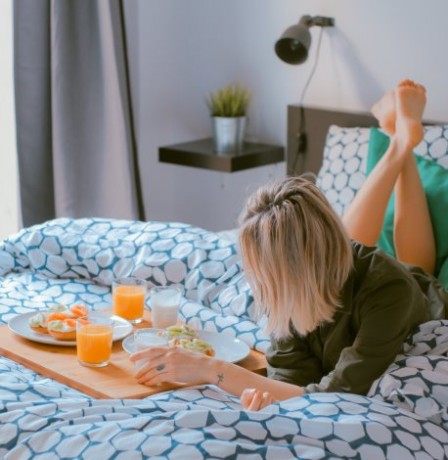 woman in hotel room eating breakfast in bed
